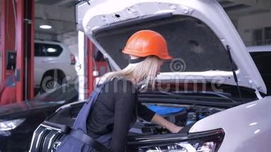 汽修车间，女机修工进入安全帽和工作服，在服务站用敞篷汽车修理破车